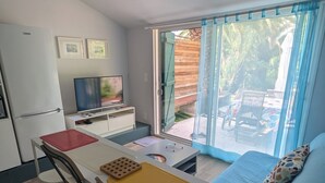Ein kompakter Wohnraum mit Küchenzeile, Essbereich und einer Schiebetür zu einer Außenpatio.