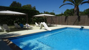 Ein Schwimmbecken mit Rutsche, Liegestühlen und Sonnenschirmen.