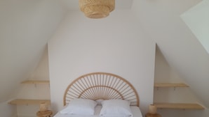 A bedroom with a sloped ceiling, a wooden bed frame, white bedding, and two bedside tables with lamps.