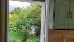 A kitchen with a window opening to a garden.