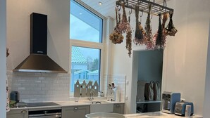 A modern kitchen with a central island, stainless steel appliances, and a hanging flower arrangement. - Lovingly furnished vacation home in the immediate vicinity of the lake (Mirow OT Granzow)