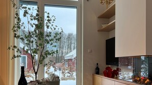 A modern living room with a large window, a potted plant, a wine bottle, and a television. - Lovingly furnished vacation home in the immediate vicinity of the lake (Mirow OT Granzow)