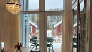 A spacious dining area with a wooden table, chairs, and a chandelier. Large windows provide a view of the outside. - Lovingly furnished vacation home in the immediate vicinity of the lake (Mirow OT Granzow)
