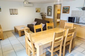 A cozy living area with a wooden dining table, chairs, a sofa, and a kitchen area with a microwave.