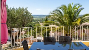 A balcony with a table and chairs, overlooking a scenic landscape with trees and a view of the countryside. - Magnificent Gite with dominant view swimming pool and jacuzzi (L'Olivier) (Langlade)