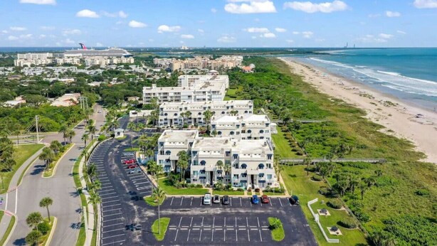 Un hotel frente a la playa con edificios de varios pisos, un estacionamiento y una carretera que serpentea por la propiedad.