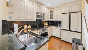 Una cocina con armarios blancos, electrodomésticos de acero inoxidable y encimeras de granito.