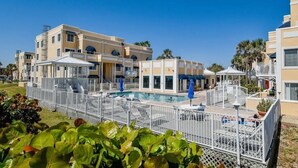 Un hotel con piscina, varios balcones y zona de piscina cercada.