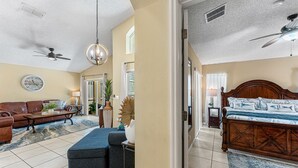 A spacious living room with a large sofa, a coffee table, and a wooden bed with a patterned bedspread. - Perfect Getaway-4Bdrm Villa W/Pool in Gated Resort (Kissimmee)