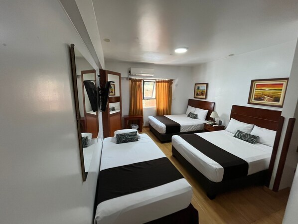 A hotel room with two beds, a mirror, a wardrobe, a desk, and a window with curtains.