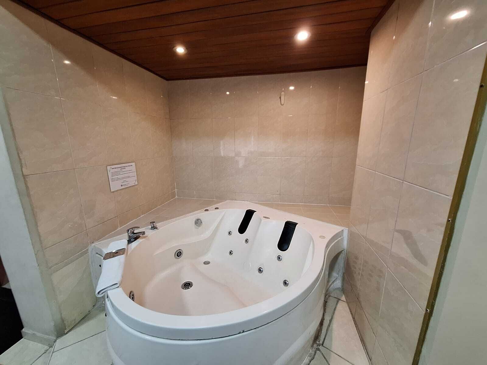A modern bathroom with a freestanding bathtub, tiled walls, and a wooden ceiling.