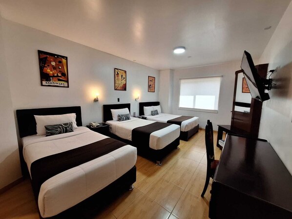 Une chambre d’hôtel avec deux lits, un bureau, une chaise et un téléviseur.