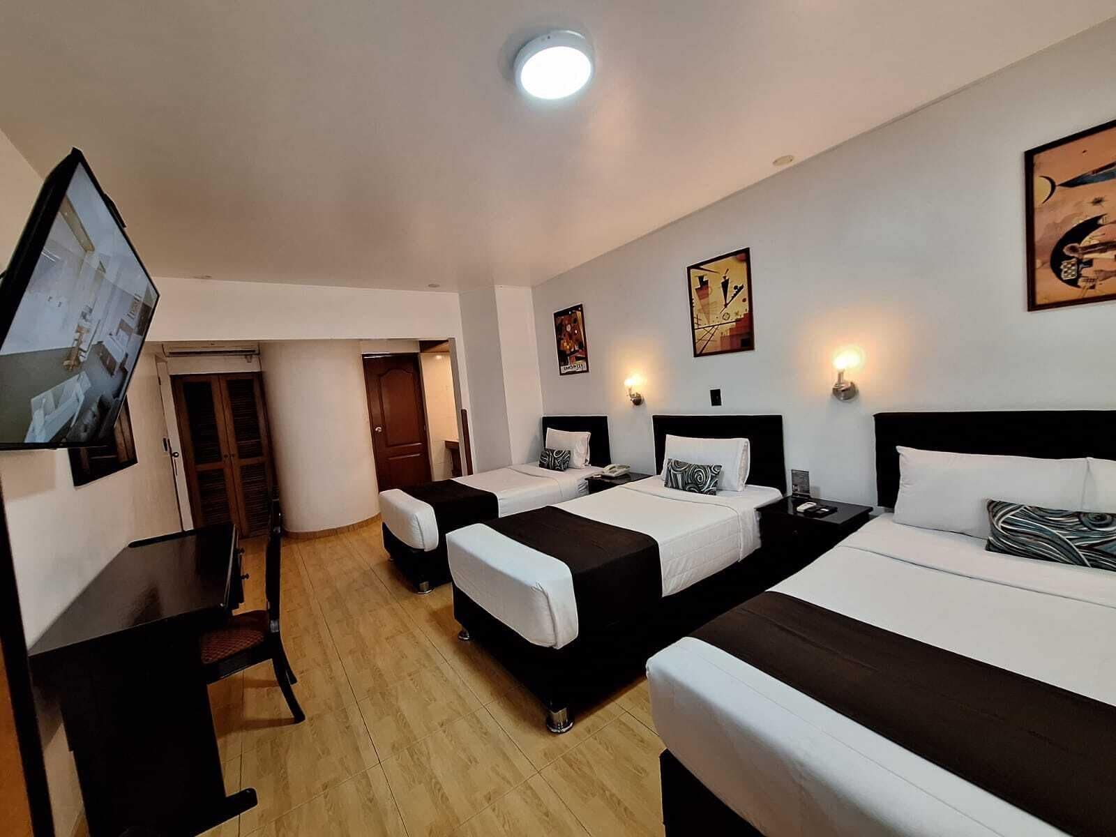 Ein Hotelzimmer mit zwei Betten, einem Fernseher und Bildern an den Wänden.