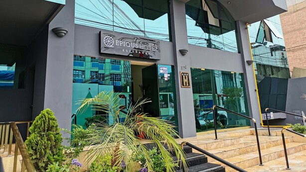 The exterior of the Epiqus Hotel with a modern design, including a glass facade and a staircase leading to the entrance. - EPIQUS HOTEL (Lima)