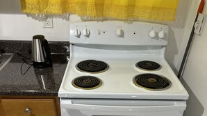 A kitchen with a white stove, a coffee maker, and wooden cabinets.