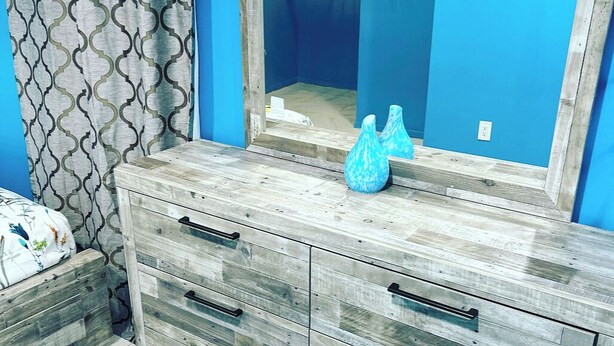 A bathroom with a wooden vanity, a large mirror, and a blue wall.