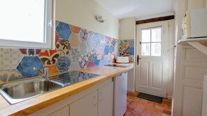 Eine Küche mit Holzarbeitsplatte, Edelstahlspüle und farbenfroher Fliesenrückwand.