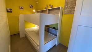 Ein kleines Zimmer mit Etagenbett, einer kleinen Regalwand und einer Wanddekoration.