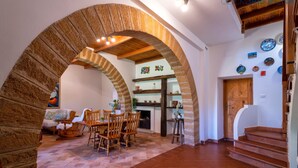 Un vaste espace de vie agrémenté d’une cheminée, de meubles en bois et d’une arche en pierre.