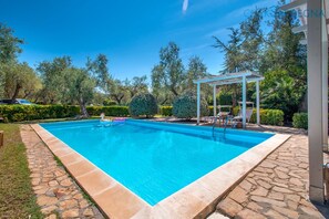 A rectangular swimming pool with a stone border, surrounded by a garden with various trees and shrubs. - ClickSardinia - Villa Cristiana, 1km from Alghero with swimming pool for exclusive use (Alghero)
