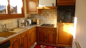 A kitchen with wooden cabinets, a stove, a microwave, and a sink. - LA COURTIONE APARTMENT IN CHALET (Samoëns)