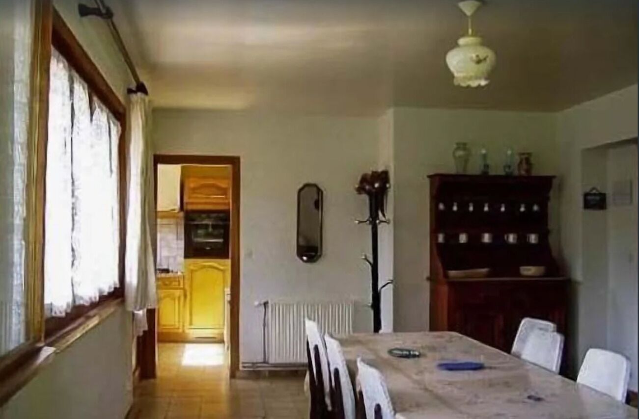 Un coin repas comprenant une table et des chaises, un radiateur, un miroir et un buffet contenant de la vaisselle.