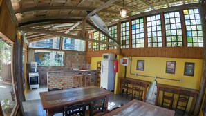 Un comedor rústico con una mesa y sillas de madera, un resguardo de ladrillo y una pared amarilla con cuadros enmarcados.