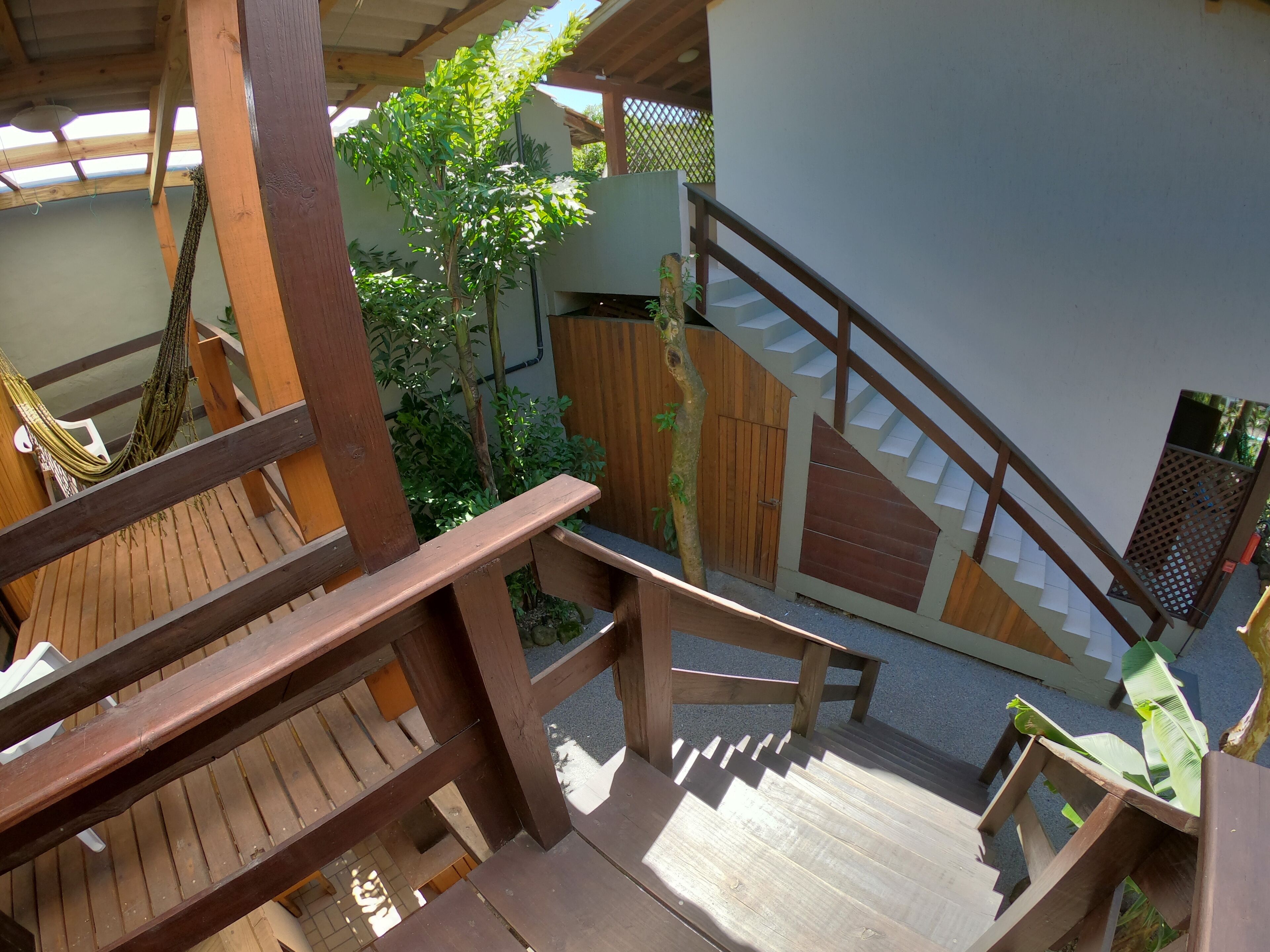 A wooden staircase leading to an upper level, surrounded by wooden railings and a hammock.