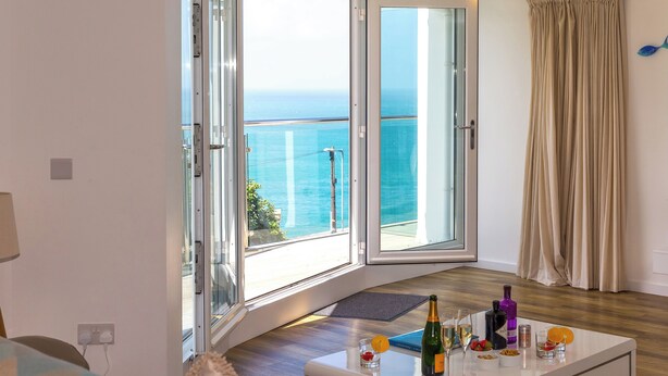 Una habitación con un gran ventanal corredizo que da a un balcón con vista al mar.