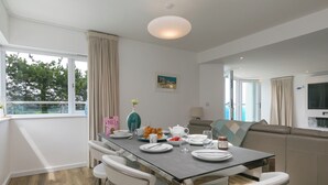 Un comedor con una mesa preparada para cuatro personas, un sofá y vistas al exterior.