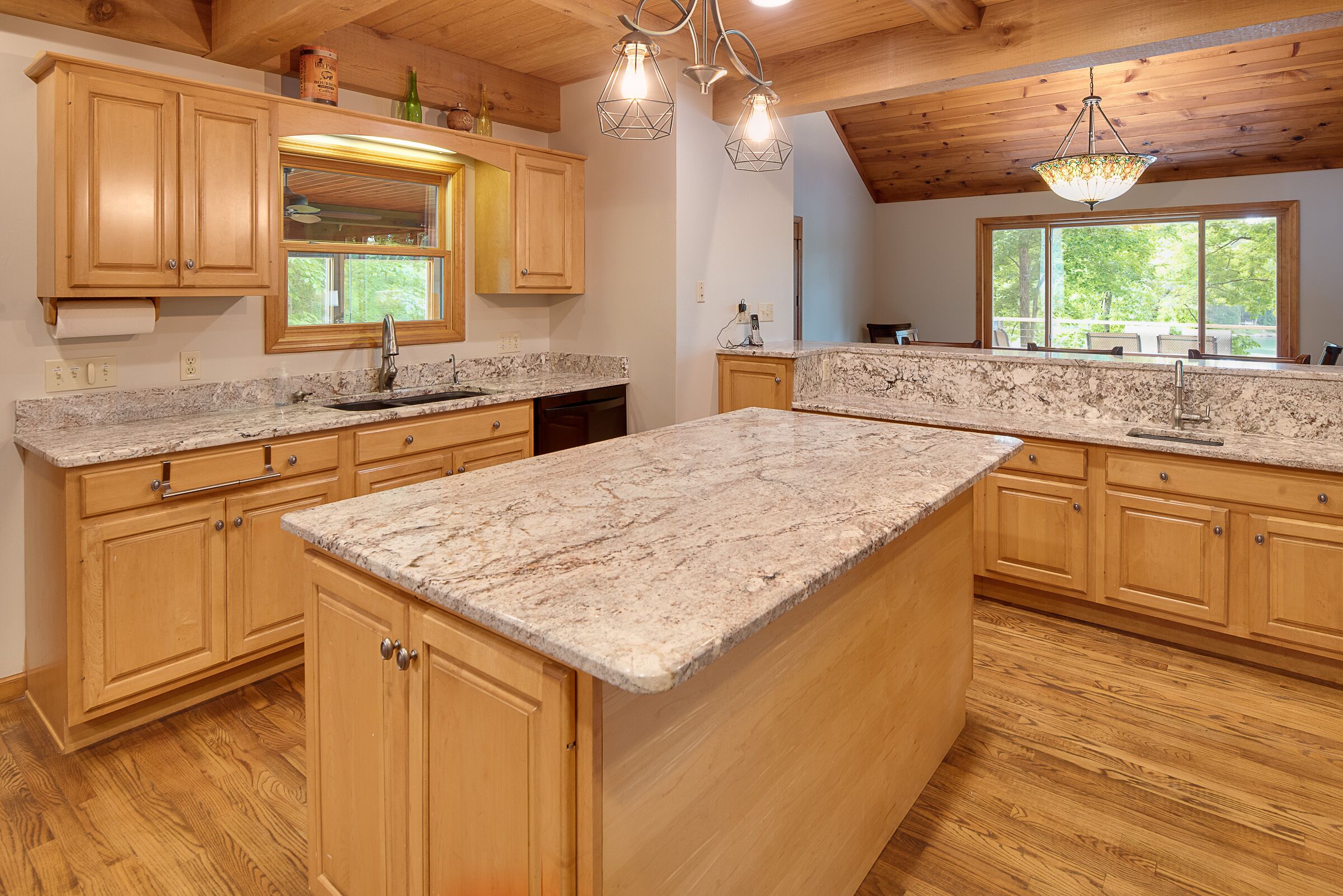 A kitchen with wooden cabinets, granite countertops, and a large island.