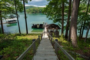 A wooden staircase leading to a dock with a covered boat and a small wooden structure.