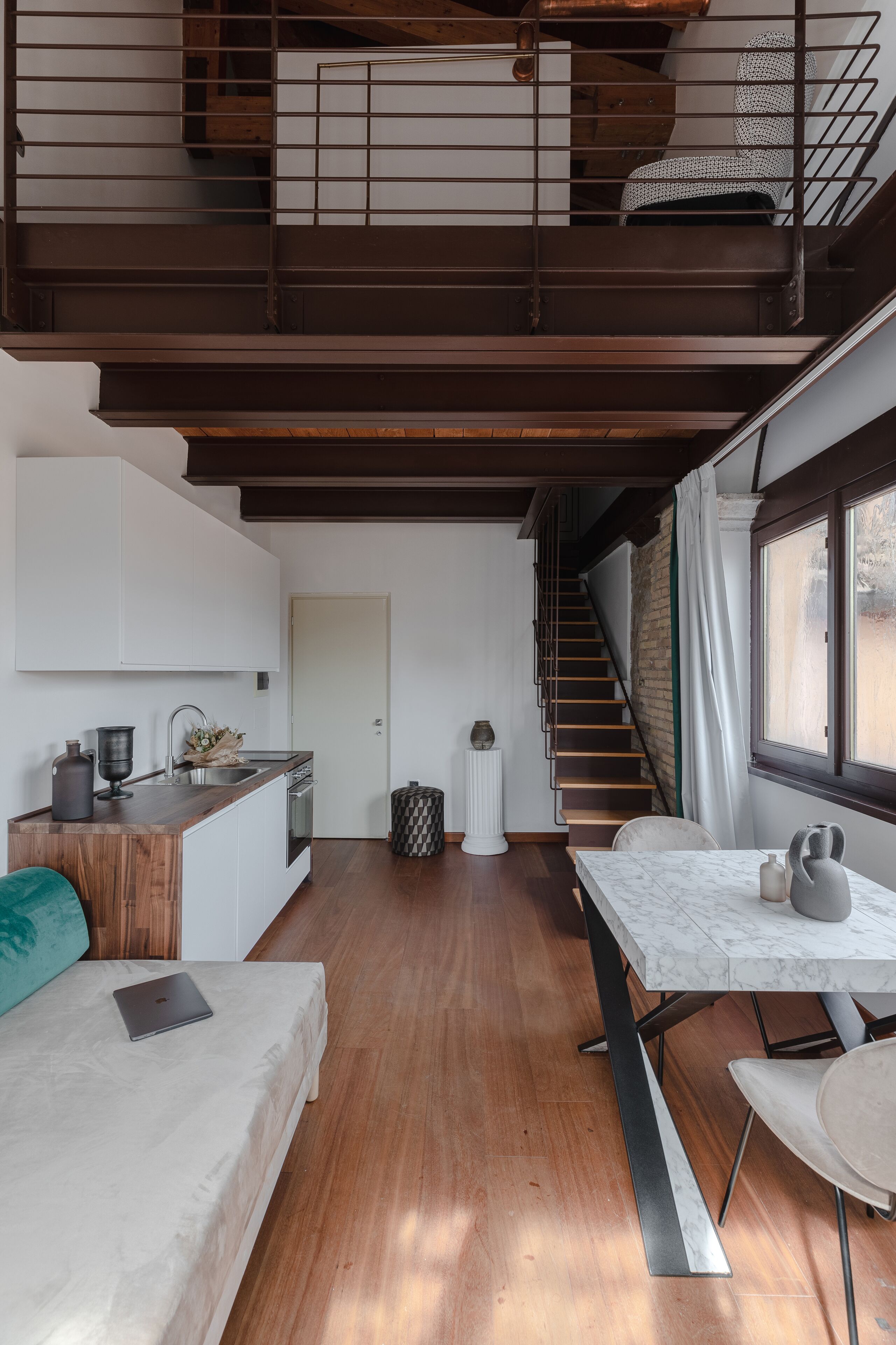 Un espace de vie compact comprenant une cuisine, un coin repas et un escalier menant à un niveau supérieur.