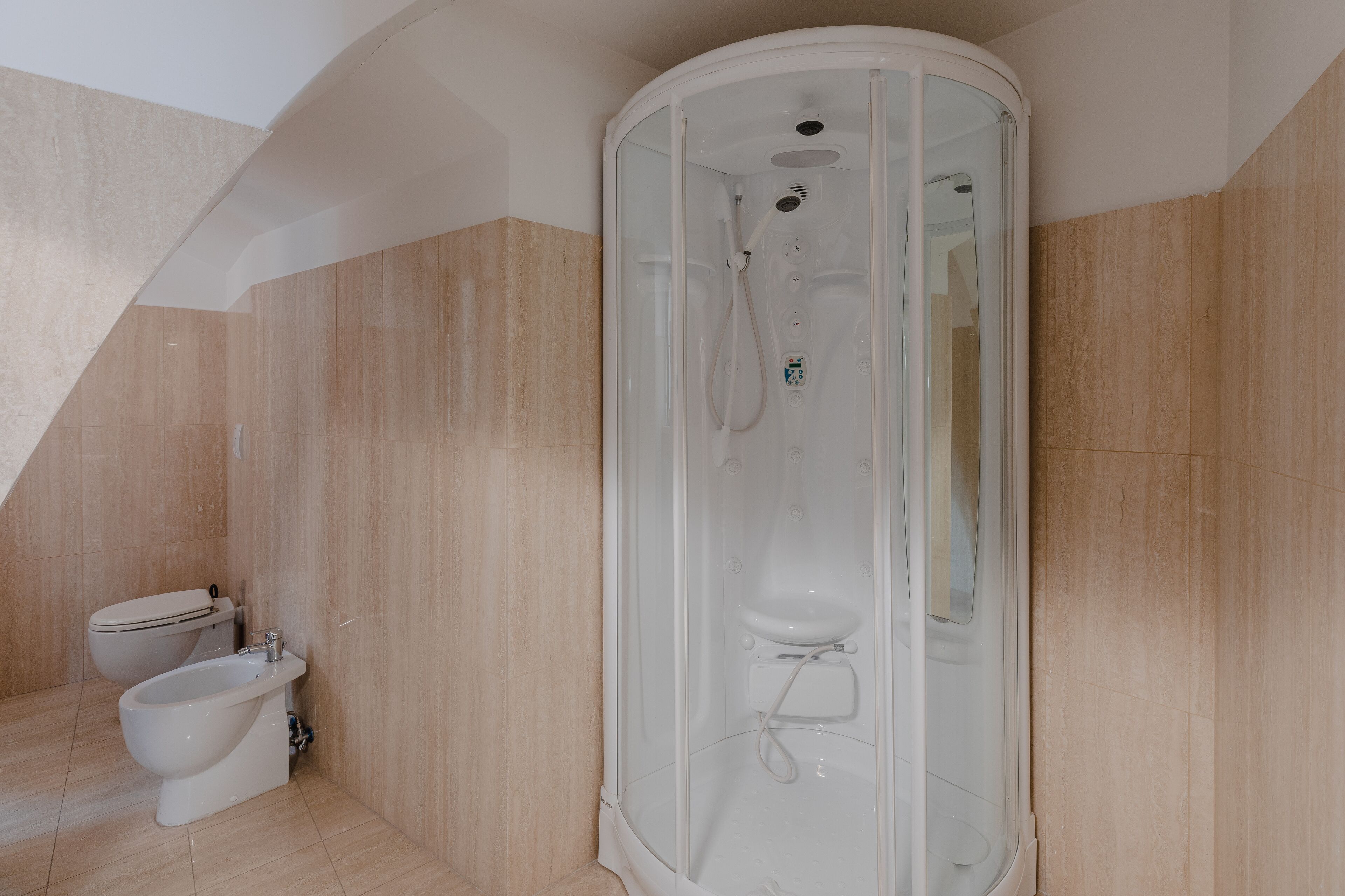 A modern bathroom with a glass-enclosed shower, a toilet, and a bidet.