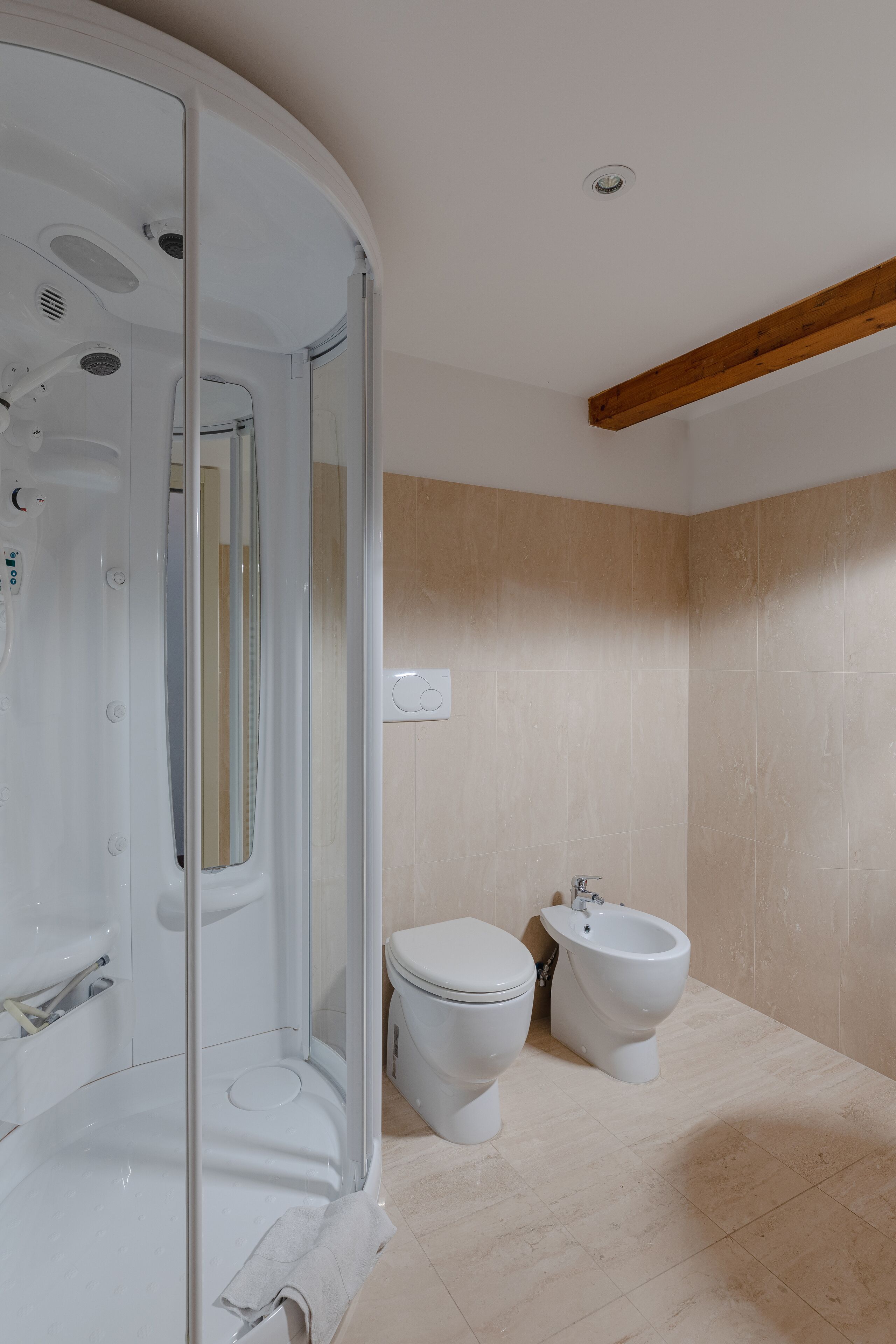 Een moderne badkamer met een douchecabine van glas, een toilet en een douchetoilet.