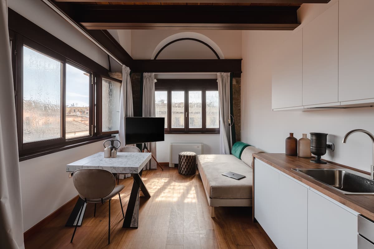 A compact kitchen with a dining area, a sofa, and a TV.