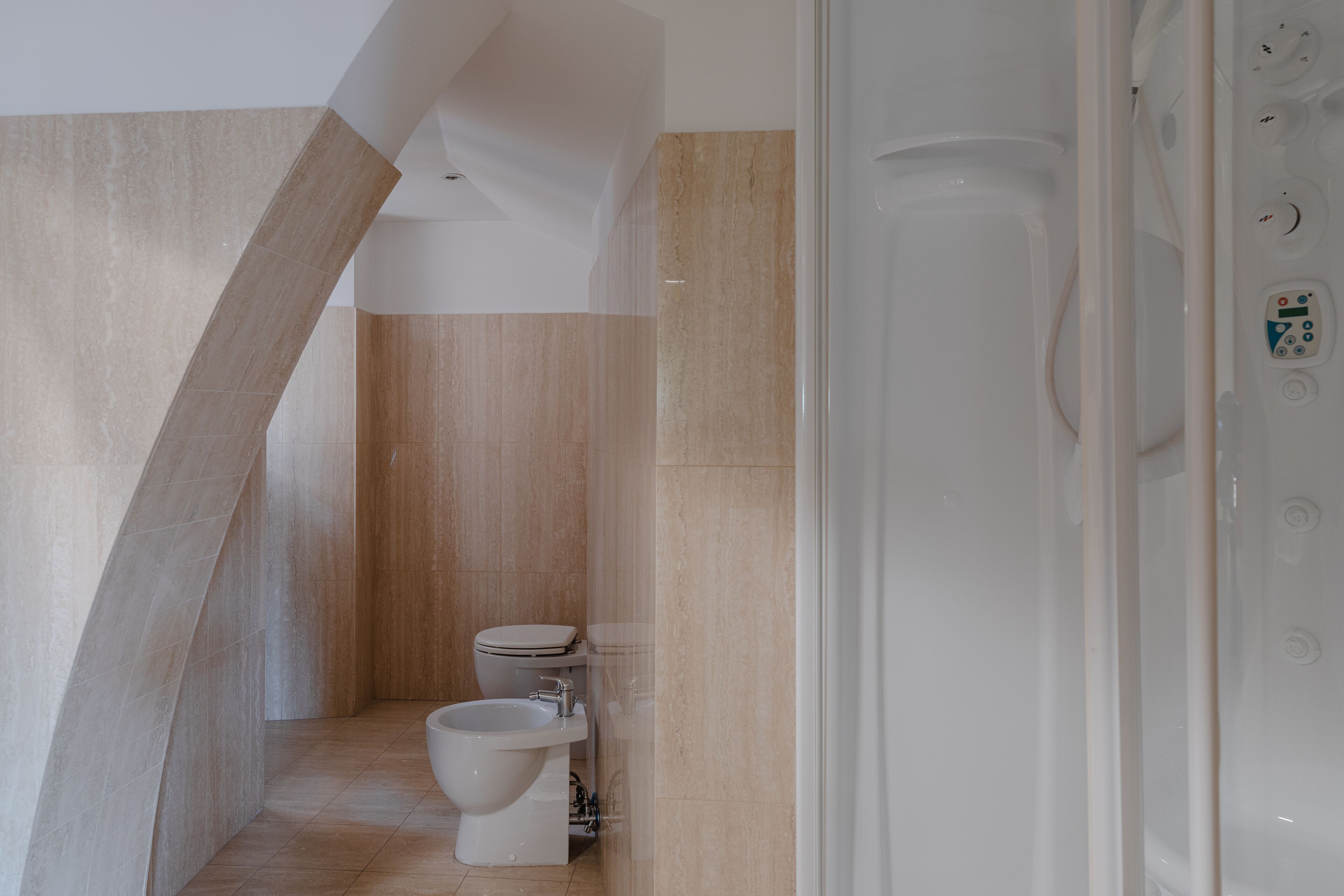 A modern bathroom with a shower, toilet, and bidet.