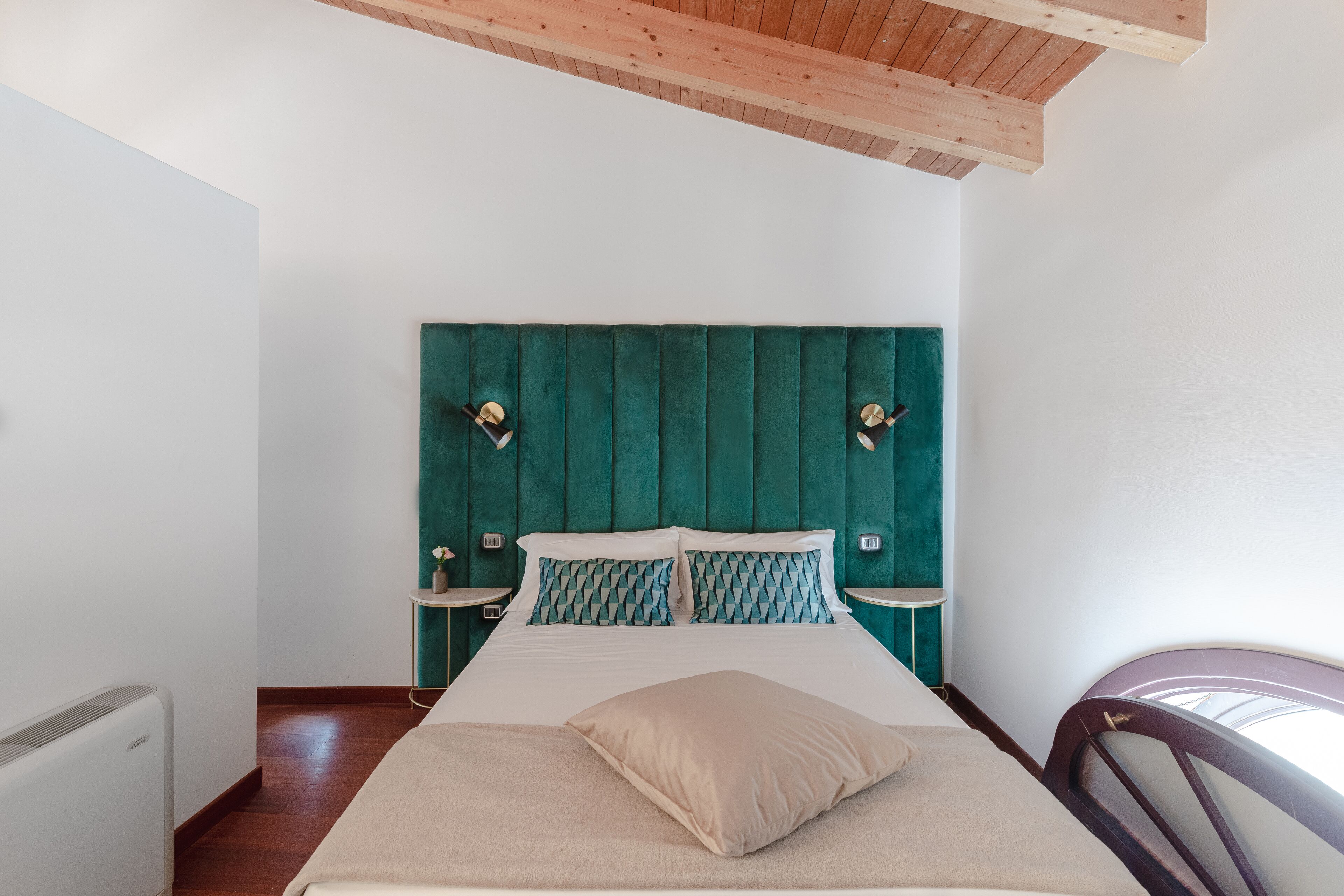 Ein Schlafzimmer mit einem Bett, einem Kopfteil, Nachttischen und einem Sessel.
