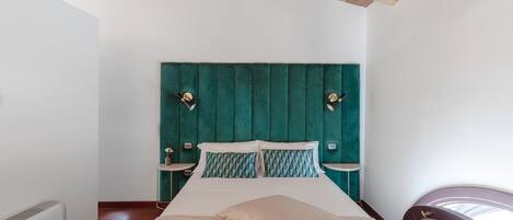 Ein Schlafzimmer mit einem Bett, einem Kopfteil, Nachttischen und einem Sessel.