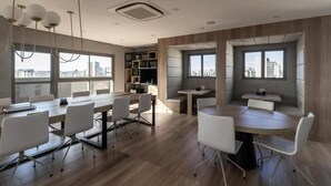 A modern office space with a large conference table, white chairs, and a city view through large windows.