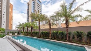 A swimming pool with palm trees and a cityscape in the background.