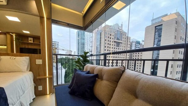 A modern hotel room with a large window, a sofa, and a bed.