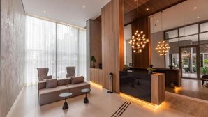 A modern lobby with a sofa, small tables, and a reception desk.