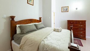 A bedroom with a wooden bed, a dresser, and two framed pictures on the wall.