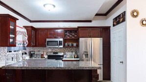 A kitchen with dark wood cabinets, a granite countertop, stainless steel appliances, and a white door.