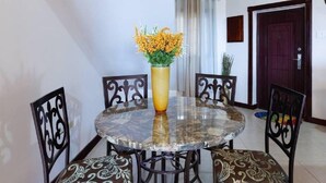A dining area with a round table, four chairs, and a vase with yellow flowers.