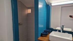 A bathroom with blue tiles, a wooden shelf with two baskets, a white sink, and a shower area. - Nice Duplex 6 persons in secured residence with swimming pool (Le Diamant)