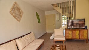 A living room with a sofa, a coffee table with bowls, a TV on a wooden cabinet, and a staircase in the background. - Nice Duplex 6 persons in secured residence with swimming pool (Le Diamant)