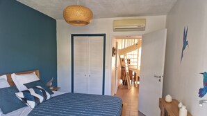 A bedroom with a bed, a wardrobe, a hanging light fixture, and a view into another room. - Nice Duplex 6 persons in secured residence with swimming pool (Le Diamant)