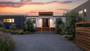 A modern house with a gravel driveway, wooden steps, and a black door. - Year-Round Heated Pool | Hot Tub | Fire Pit | Huge Lawn | Vineyard Views (Kenwood)